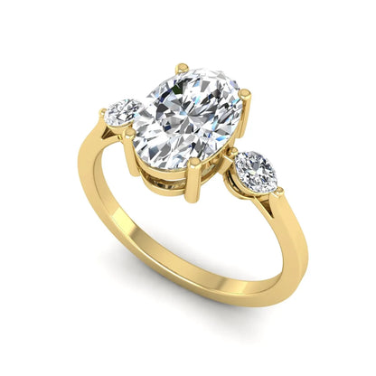 Oval cut lab grown diamond three stone engagement ring with marquise side diamonds in a prong setting featuring a yellow gold tone design.