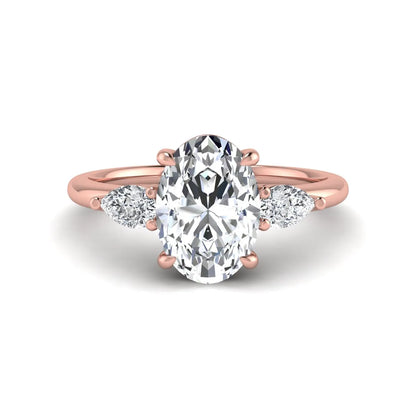 Oval cut lab grown diamond three stone engagement ring with pear side diamonds in a prong setting featuring a rose gold tone design.
