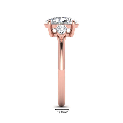 Oval cut lab grown diamond three stone engagement ring with pear side diamonds in a prong setting featuring a rose gold tone design.