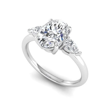 Oval cut lab grown diamond three stone engagement ring with pear side diamonds in a prong setting featuring a white gold tone design.