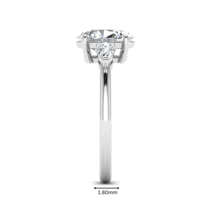 Oval cut lab grown diamond three stone engagement ring with pear side diamonds in a prong setting featuring a white gold tone design.