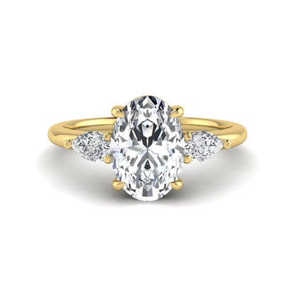 Oval cut lab grown diamond three stone engagement ring with pear side diamonds in a prong setting featuring a yellow gold tone design.