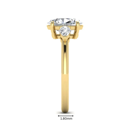 Oval cut lab grown diamond three stone engagement ring with pear side diamonds in a prong setting featuring a yellow gold tone design.