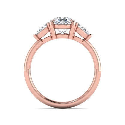 Oval cut lab grown diamond three stone engagement ring with pear cut side diamonds in a prong setting on a polished rose gold band.