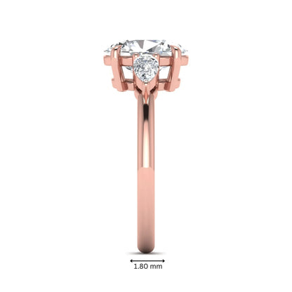 Oval cut lab grown diamond three stone engagement ring with pear cut side diamonds in a prong setting on a polished rose gold band.