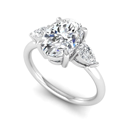 Oval cut lab grown diamond three stone engagement ring with pear cut side diamonds in a prong setting on a polished white gold band.