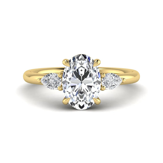 Oval cut lab grown diamond three stone engagement ring with pear cut side diamonds in a prong setting on a polished yellow gold band.