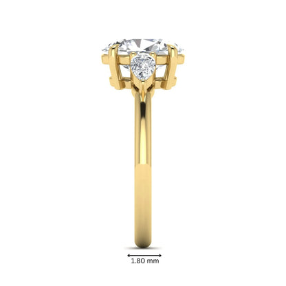 Oval cut lab grown diamond three stone engagement ring with pear cut side diamonds in a prong setting on a polished yellow gold band.