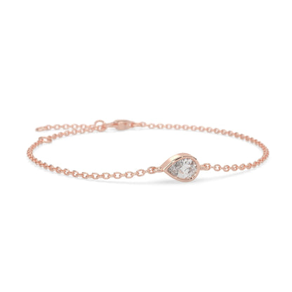 Pear cut lab grown diamond bezel set solitaire bracelet with delicate chain and lobster clasp in rose gold tone.