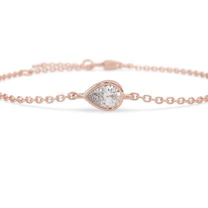 Pear cut lab grown diamond bezel set solitaire bracelet with delicate chain and lobster clasp in rose gold tone.
