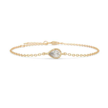 Pear cut lab grown diamond bezel set solitaire bracelet with delicate chain and lobster clasp in yellow gold tone.