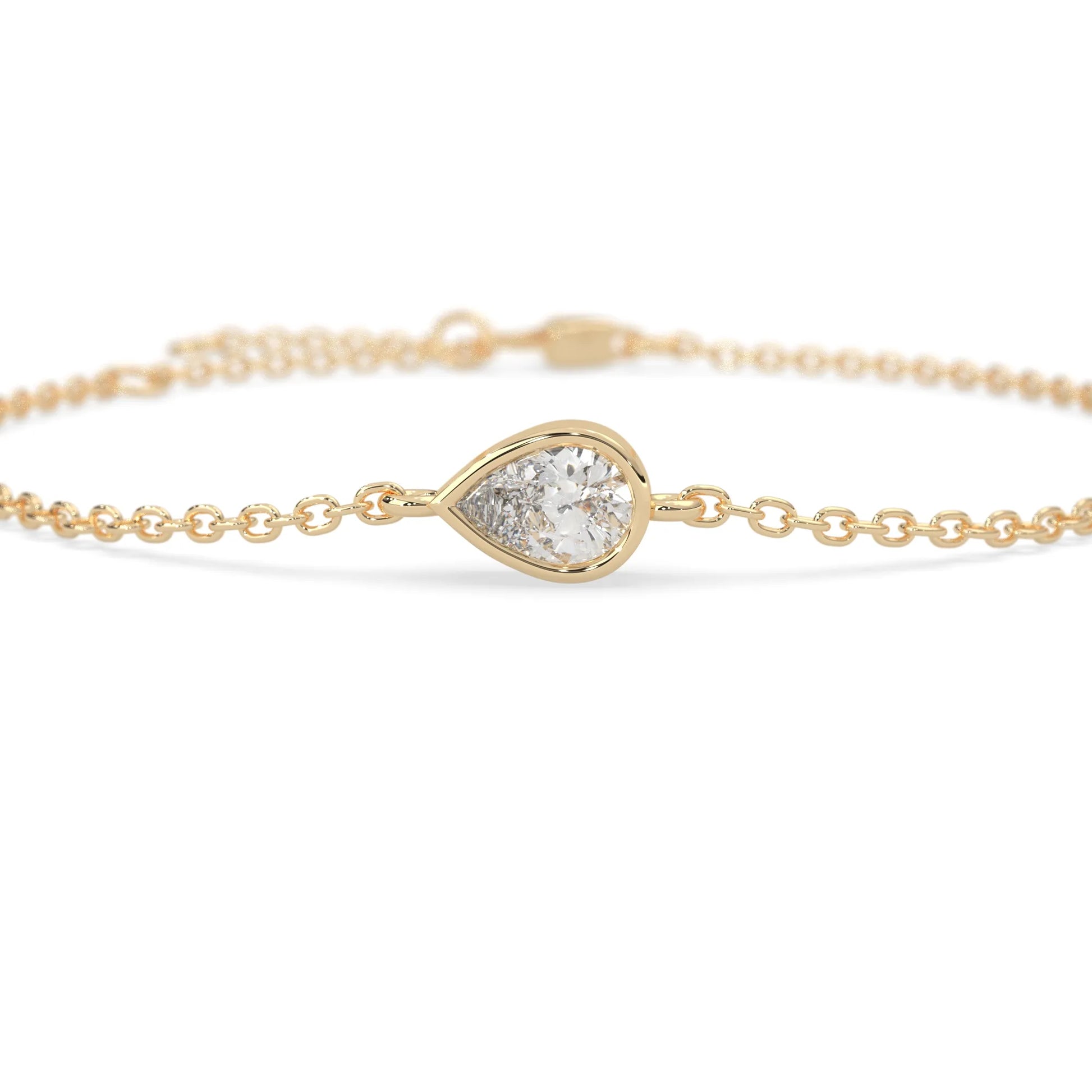 Pear cut lab grown diamond bezel set solitaire bracelet with delicate chain and lobster clasp in yellow gold tone.