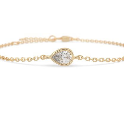 Pear cut lab grown diamond bezel set solitaire bracelet with delicate chain and lobster clasp in yellow gold tone.