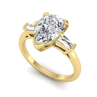 Pear cut lab grown diamond three stone engagement ring featuring a 2.31 carat IGI certified center diamond with tapered baguette side diamonds in yellow gold.