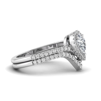 Pear cut lab grown diamond bridal ring set featuring a halo engagement ring with a matching curved pavé wedding band in a white gold tone design.