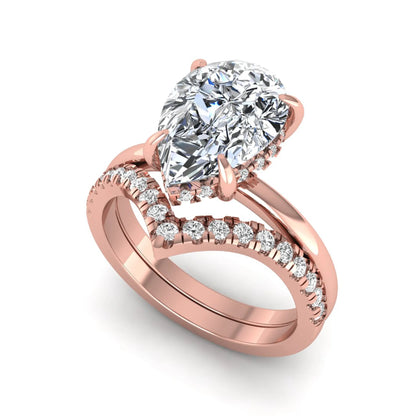 Pear cut lab grown diamond hidden halo solitaire bridal ring set featuring a four-prong engagement ring with a matching pavé chevron wedding band in rose gold.