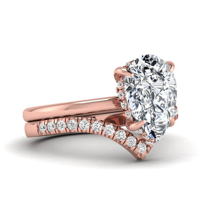 Pear cut lab grown diamond hidden halo solitaire bridal ring set featuring a four-prong engagement ring with a matching pavé chevron wedding band in rose gold.
