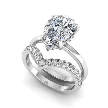 Pear cut lab grown diamond hidden halo solitaire bridal ring set featuring a four-prong engagement ring with a matching pavé chevron wedding band in white gold.