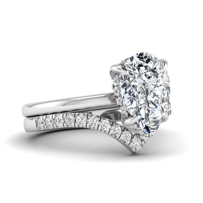 Pear cut lab grown diamond hidden halo solitaire bridal ring set featuring a four-prong engagement ring with a matching pavé chevron wedding band in white gold.