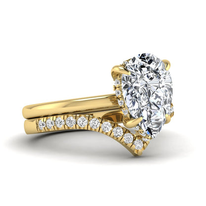 Pear cut lab grown diamond hidden halo solitaire bridal ring set featuring a four-prong engagement ring with a matching pavé chevron wedding band in yellow gold.