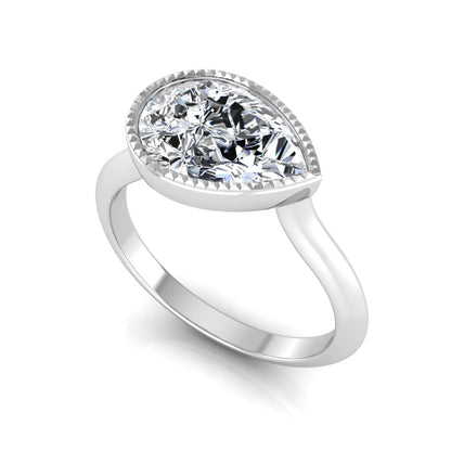 Pear cut lab grown diamond solitaire engagement ring featuring a milgrain bezel setting with a white gold tone band.
