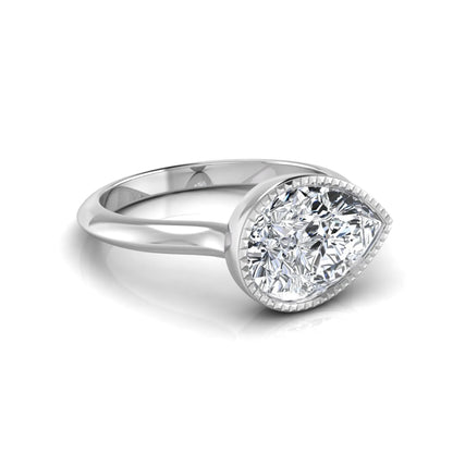 Pear cut lab grown diamond solitaire engagement ring featuring a milgrain bezel setting with a white gold tone band.