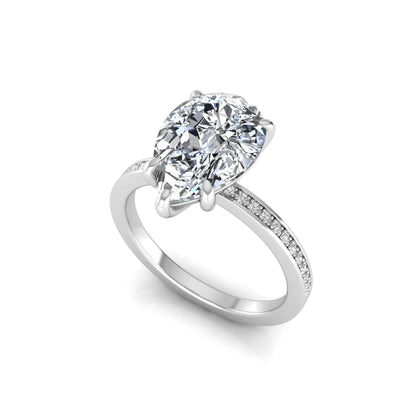 Pear cut lab grown diamond solitaire engagement ring featuring a five-prong setting with a pavé diamond band in white gold tone.