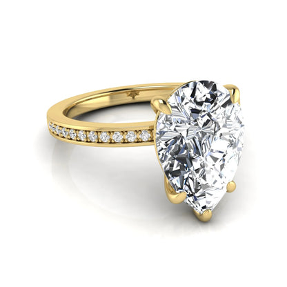 Pear cut lab grown diamond solitaire engagement ring featuring a five-prong setting with a pavé diamond band in yellow gold tone.