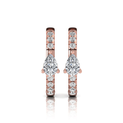 Pear and round cut lab grown diamond pavé huggie hoop earrings featuring a three prong pear diamond center, shared prong round diamond accents, hinged snap closure, and polished rose gold finish.