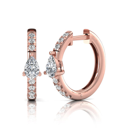 Pear and round cut lab grown diamond pavé huggie hoop earrings featuring a three prong pear diamond center, shared prong round diamond accents, hinged snap closure, and polished rose gold finish.