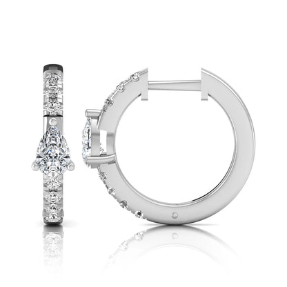 Pear and round cut lab grown diamond pavé huggie hoop earrings featuring a three prong pear diamond center, shared prong round diamond accents, hinged snap closure, and polished white gold finish.