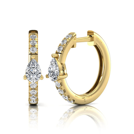 Pear and round cut lab grown diamond pavé huggie hoop earrings featuring a three prong pear diamond center, shared prong round diamond accents, hinged snap closure, and polished yellow gold finish.