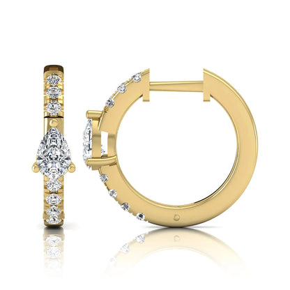Pear and round cut lab grown diamond pavé huggie hoop earrings featuring a three prong pear diamond center, shared prong round diamond accents, hinged snap closure, and polished yellow gold finish.