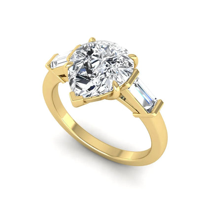Pear cut lab grown diamond three stone engagement ring with baguette side diamonds in a classic prong setting in yellow gold