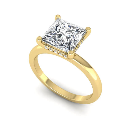 Princess cut lab grown diamond hidden halo solitaire engagement ring with four-prong setting and yellow gold tone band.