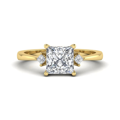 Princess cut lab grown diamond three stone engagement ring featuring a four-prong center diamond with princess cut side stones in yellow gold.