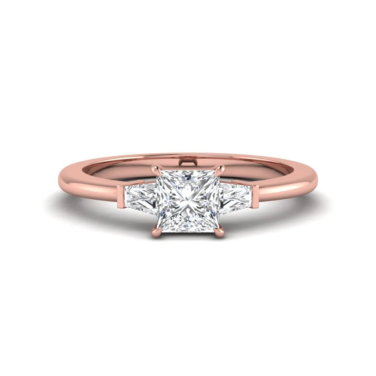 Princess cut lab grown diamond three stone engagement ring with tapered baguette side diamonds in a four-prong setting and rose gold tone band.