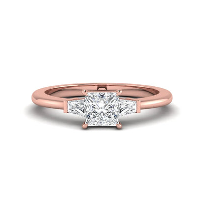 Princess cut lab grown diamond three stone engagement ring with tapered baguette side diamonds in a four-prong setting and rose gold tone band.