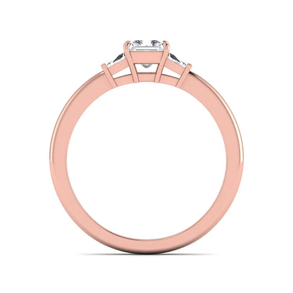 Princess cut lab grown diamond three stone engagement ring with tapered baguette side diamonds in a four-prong setting and rose gold tone band.