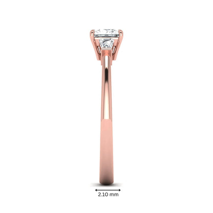 Princess cut lab grown diamond three stone engagement ring with tapered baguette side diamonds in a four-prong setting and rose gold tone band.