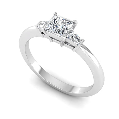 Princess cut lab grown diamond three stone engagement ring with tapered baguette side diamonds in a four-prong setting and white gold tone band.
