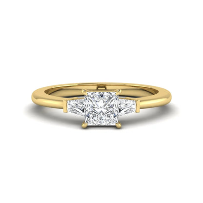 Princess cut lab grown diamond three stone engagement ring with tapered baguette side diamonds in a four-prong setting and yellow gold tone band.