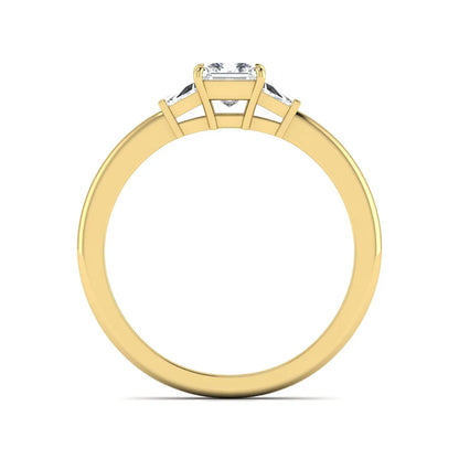 Princess cut lab grown diamond three stone engagement ring with tapered baguette side diamonds in a four-prong setting and yellow gold tone band.