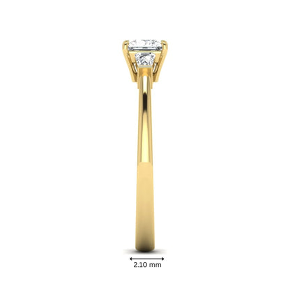 Princess cut lab grown diamond three stone engagement ring with tapered baguette side diamonds in a four-prong setting and yellow gold tone band.