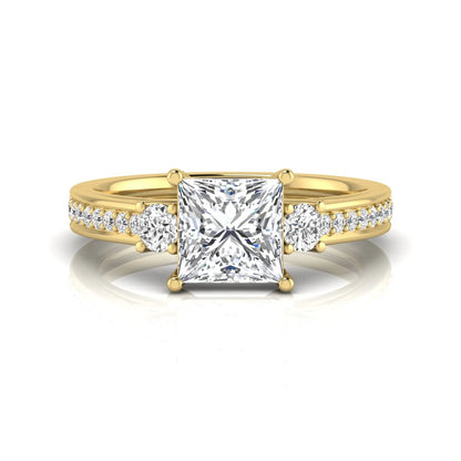 Princess cut three stone lab grown diamond engagement ring featuring a princess center diamond, round side diamonds, and pavé band in yellow metal tone.