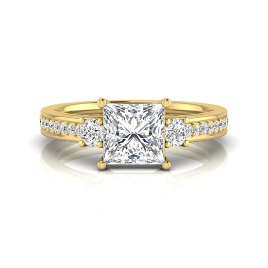 Princess cut three stone lab grown diamond engagement ring featuring a princess center diamond, round side diamonds, and pavé band in yellow metal tone.