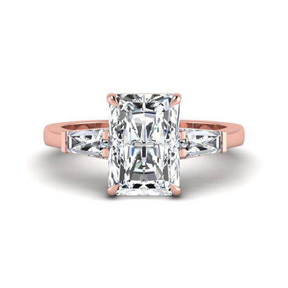 Radiant cut lab grown diamond three stone engagement ring with tapered baguette side diamonds and four prong setting in rose gold tone.