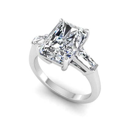 Radiant cut lab grown diamond three stone engagement ring with tapered baguette side diamonds and four prong setting in white gold tone.