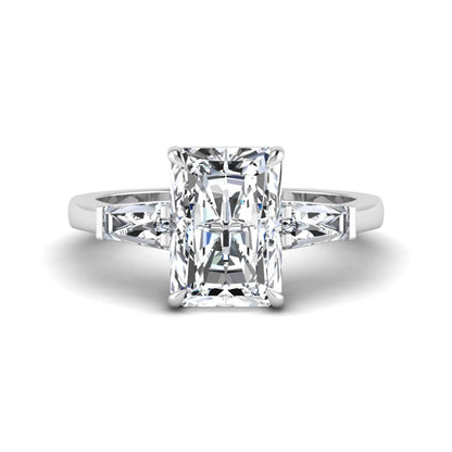 Radiant cut lab grown diamond three stone engagement ring with tapered baguette side diamonds and four prong setting in white gold tone.