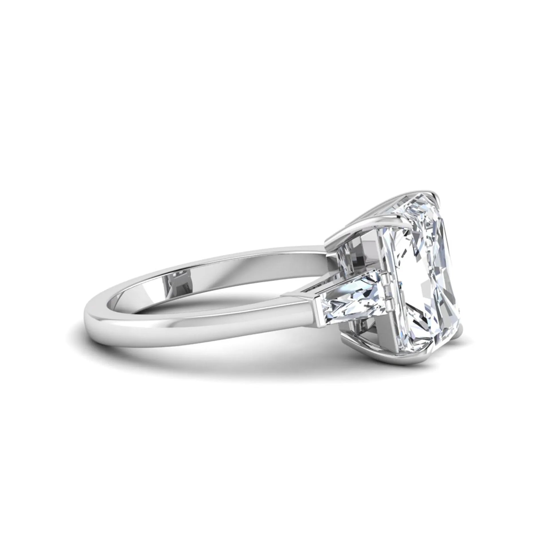 Radiant cut lab grown diamond three stone engagement ring with tapered baguette side diamonds and four prong setting in white gold tone.